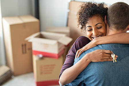 couple hugging with boxes behind them
