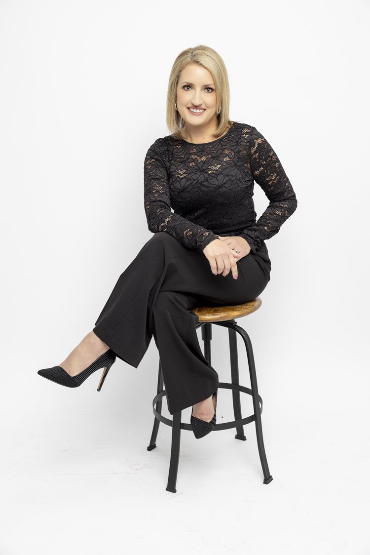 blonde women in all black sitting on stool for professional headshot
