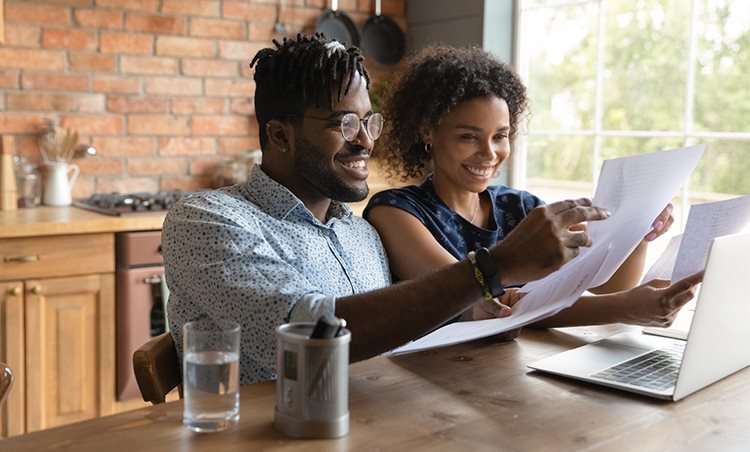 Young couple sitting in front of a laptop looking at papers